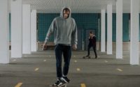 Two people skateboarding indoors in an urban parking lot.