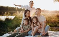 A family of five enjoying a serene picnic in a sunlit meadow during sunset.